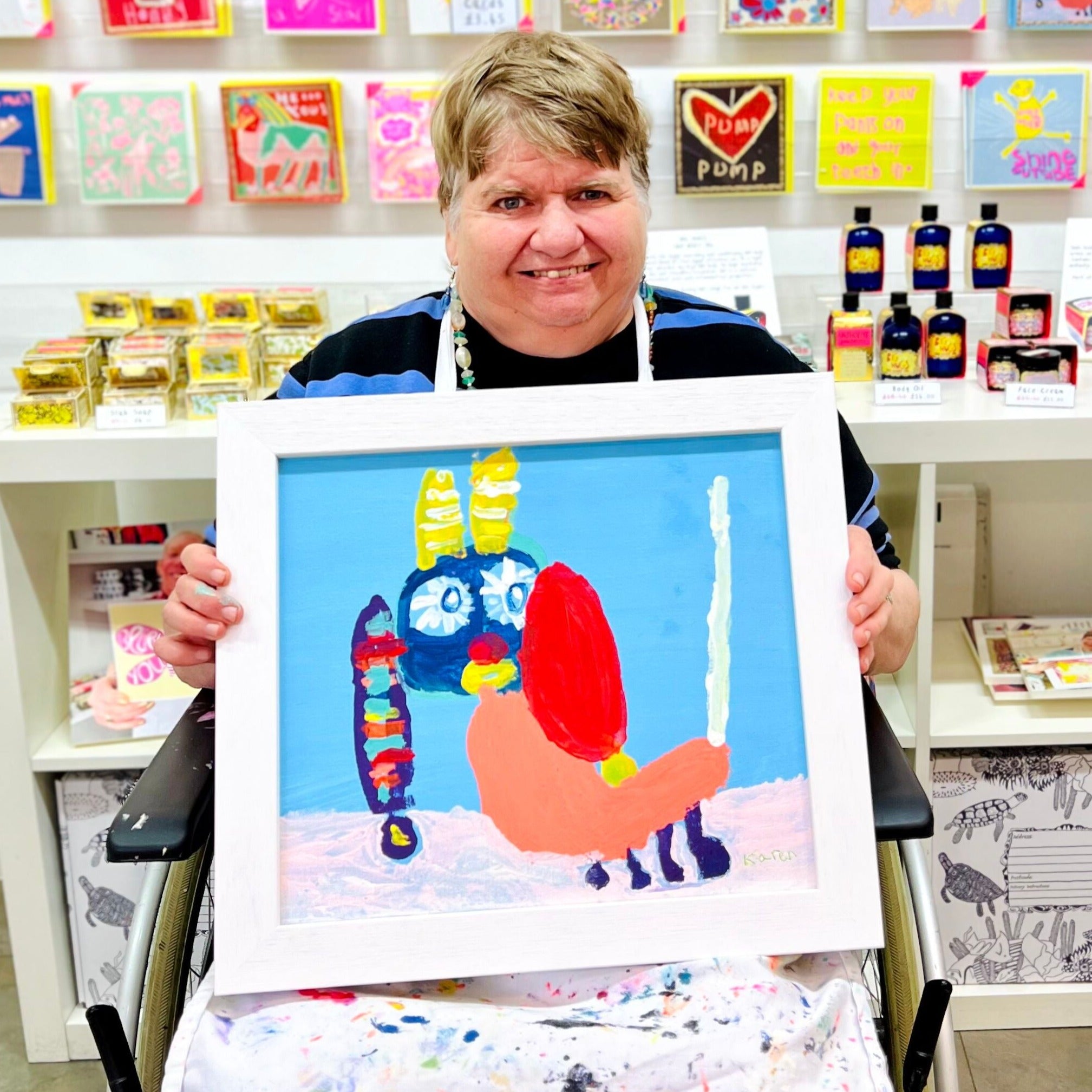Artist holding Framed painting of a colourful dog in blues and oranges with a happy face