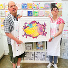 Two artists holding Framed painting of blue, pink and yellow birds