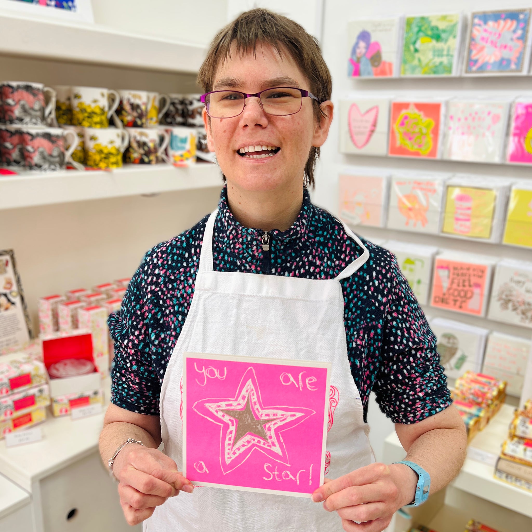 A female artist holding A pink and gold card with a hand drawn star and the words you are a star!