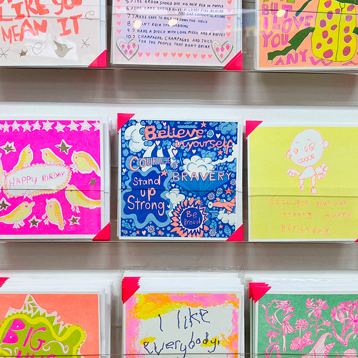 A rack of cards focusing on A blue and orange card with uplifting messages hand drawn onto it such as Believe in your self and bravery 
