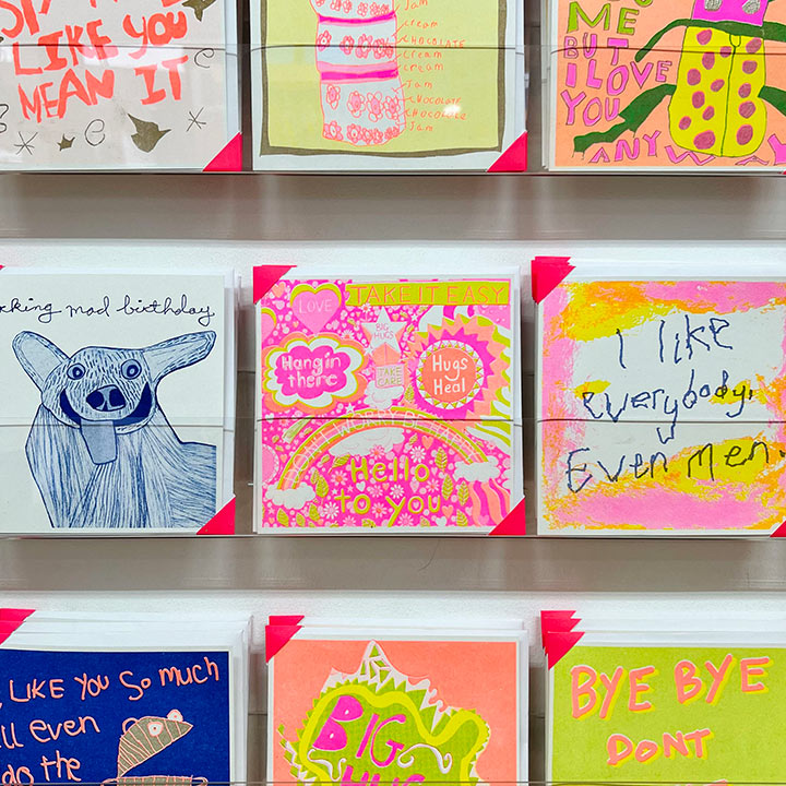 A card rack focusing on A bright pink, orange and yellow card with positive messages including the words take it easy