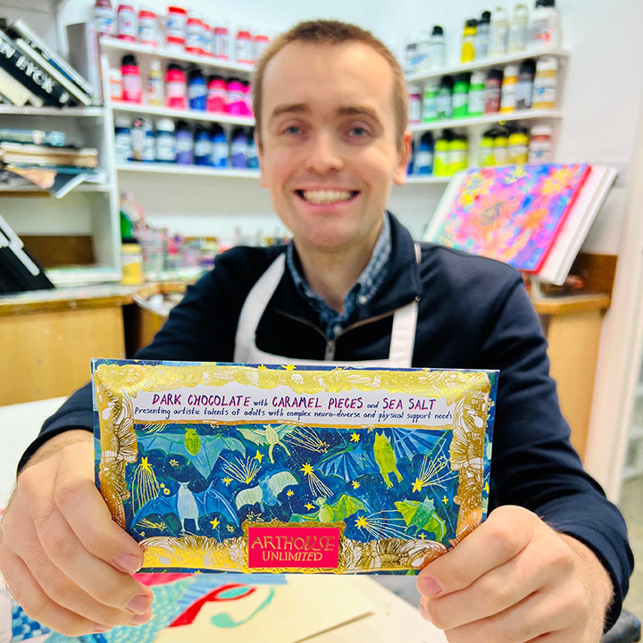 Male artist holding Bat Mates dark chocolate bar with caramel and sea salt
