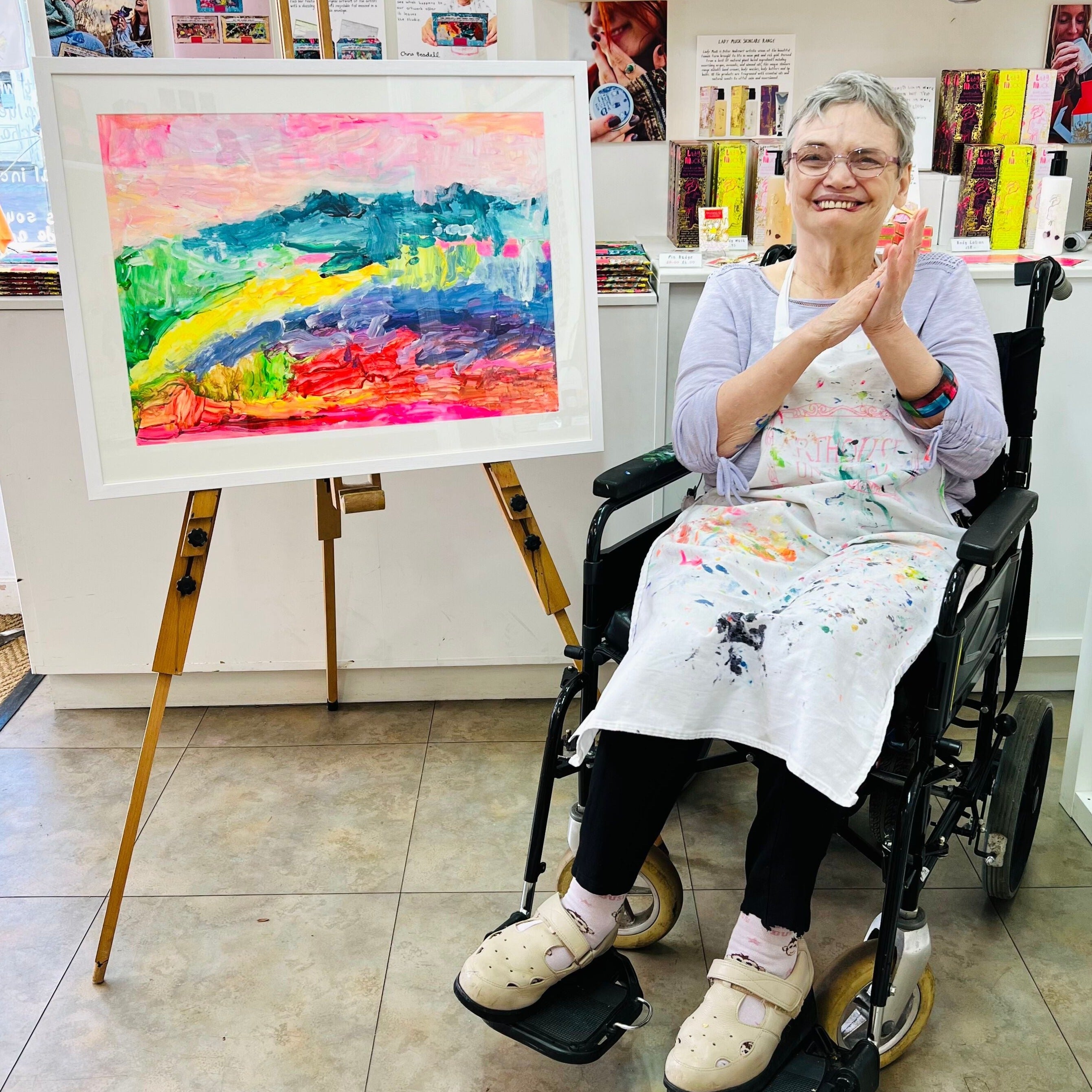 female artist holding Framed painting of a colourful landscape