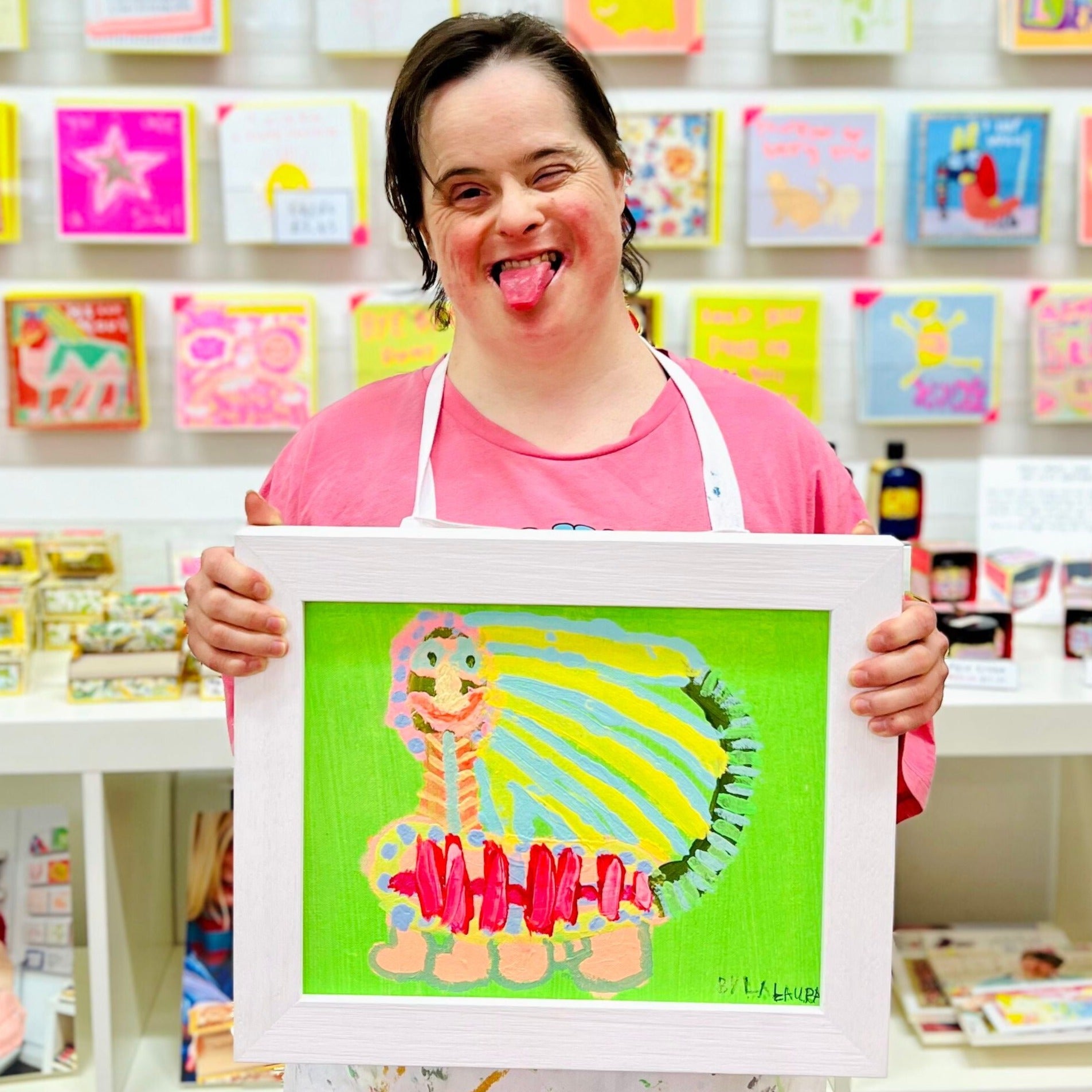 Female artist holding a framed painting of a green, yellow and pink caterpillar