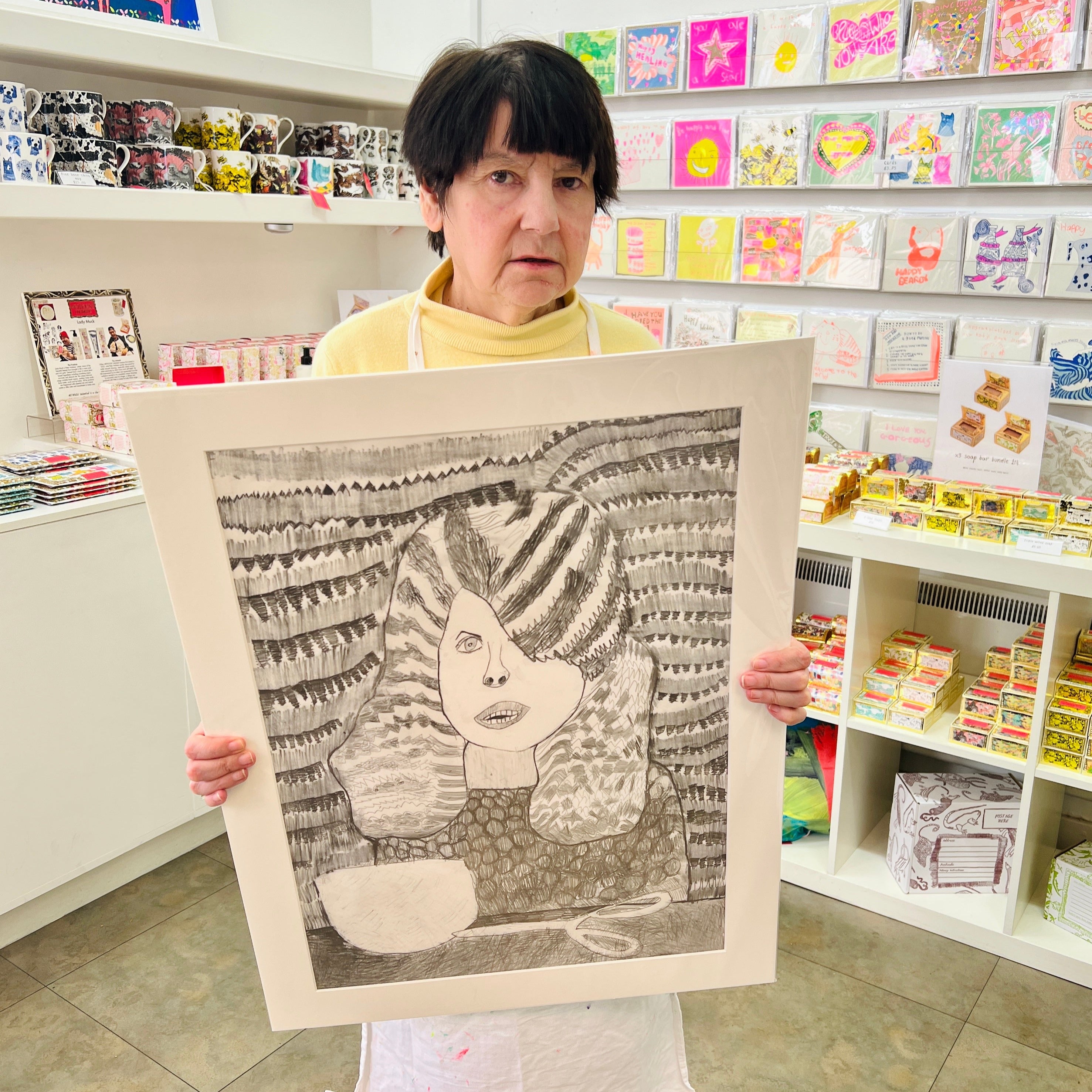Female artist holding Hand drawn picture in pencil of a woman at the hairdressers