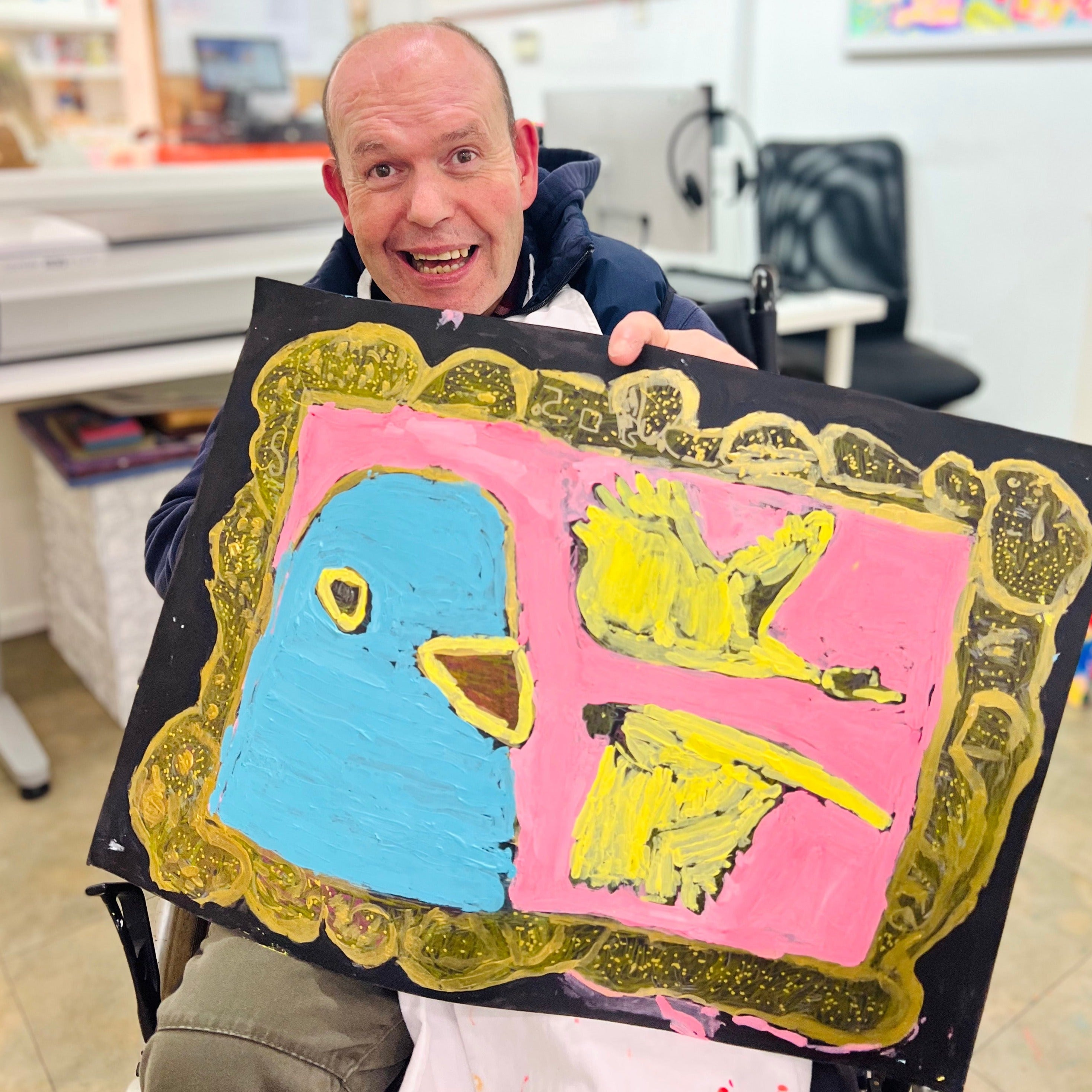 male artist holding Framed painting of 3 pigeons in pink, gold and blue
