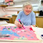 Female artist in a studio drawing a picture of stacked animals in pink 