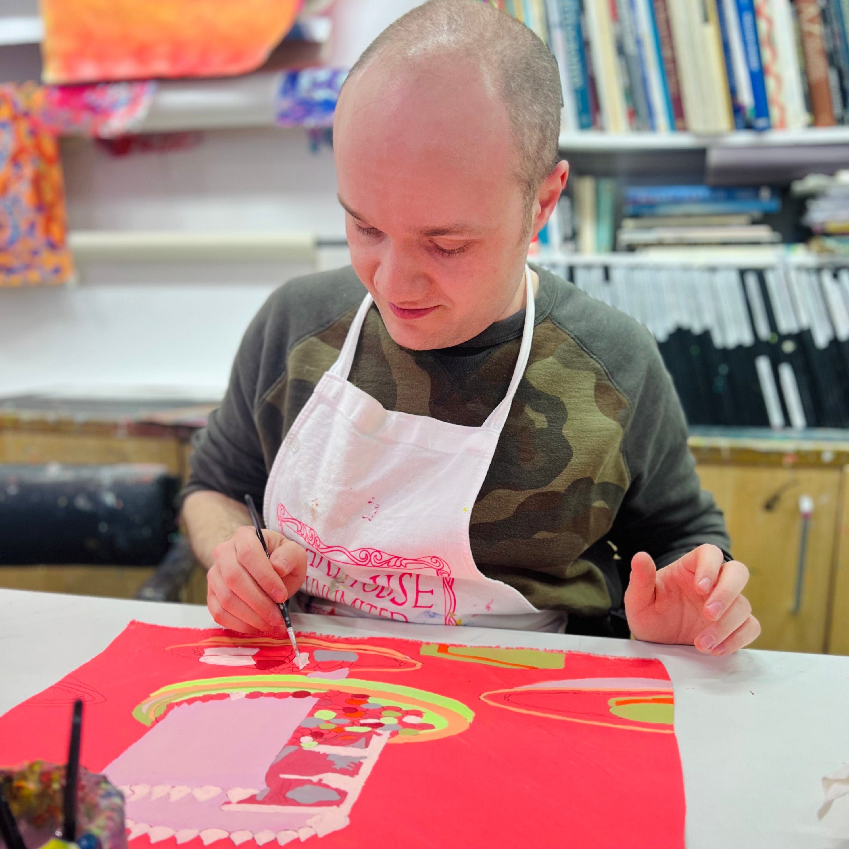 Male artist painting a bright coloured celebration cake
