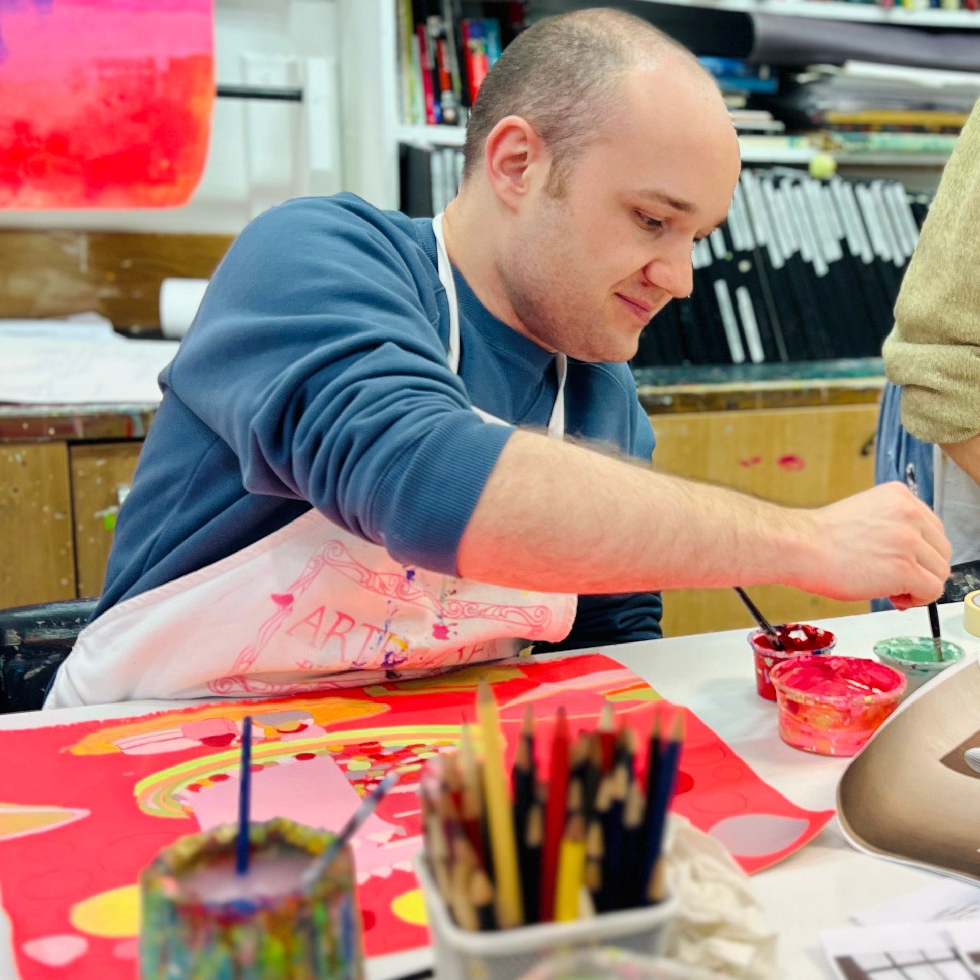 Male artist in a studio painting a bright coloured celebration cake