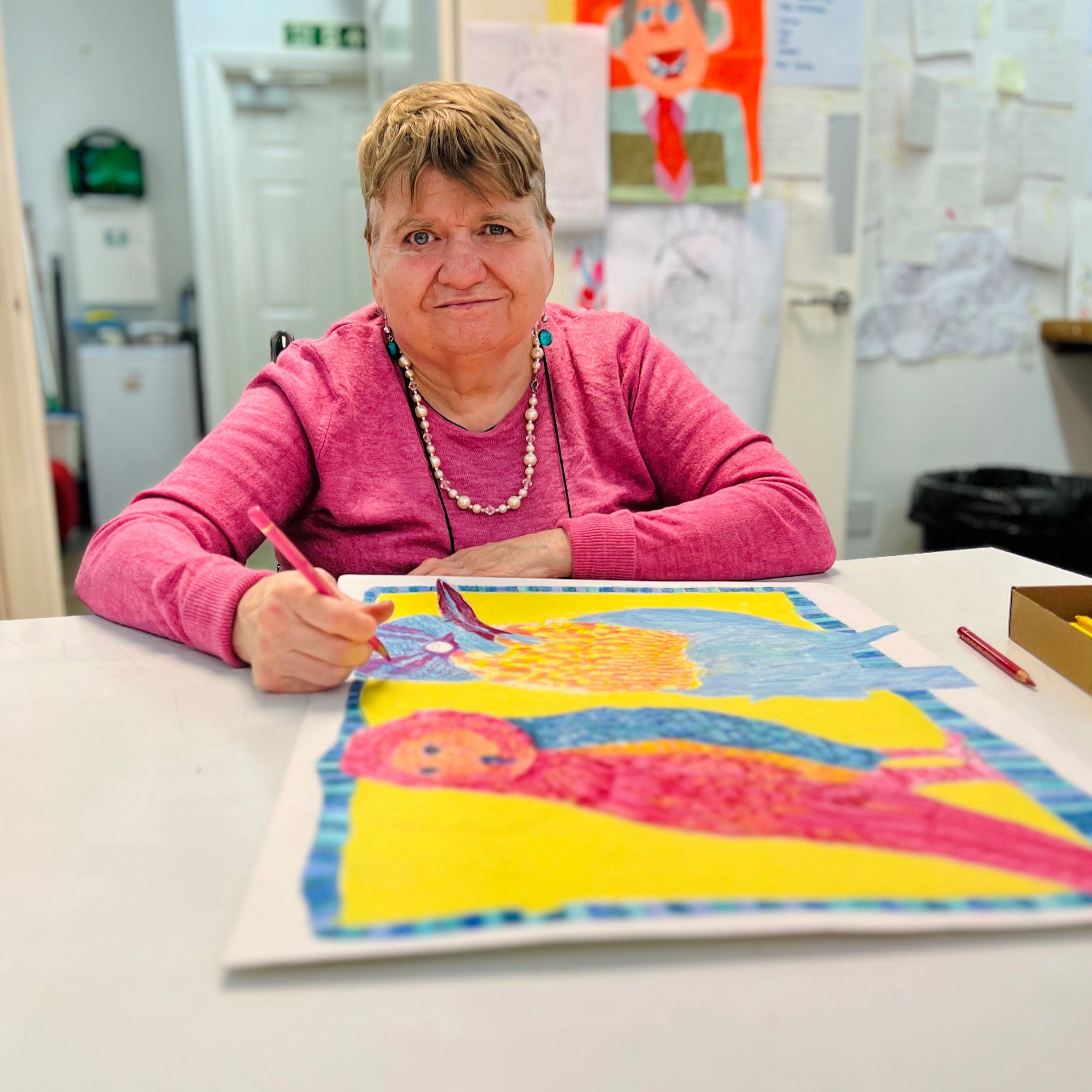Female artist drawing bright coloured birds with pencil in a studio