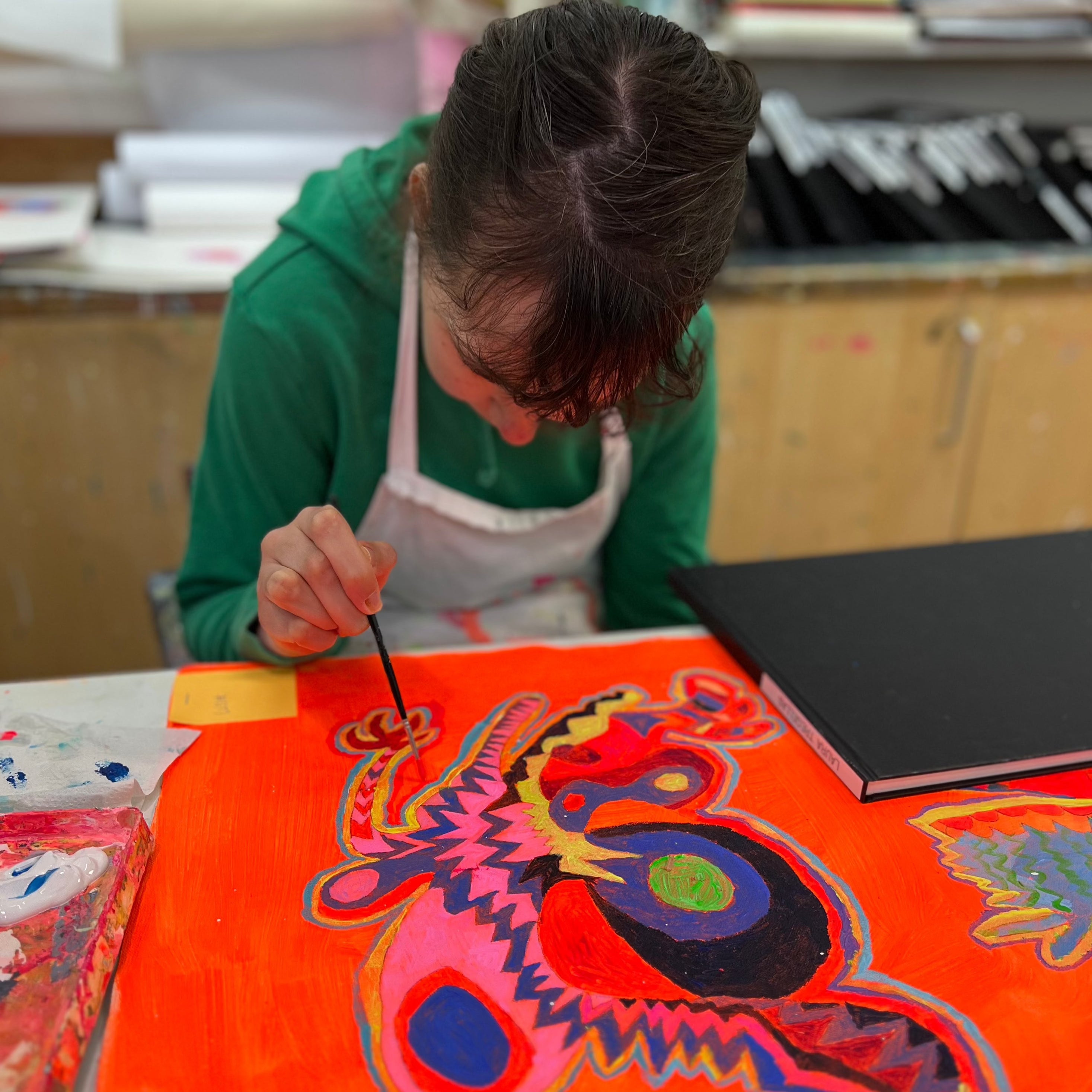 Female artist painting a bright coloured strange creatures