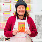 Female artist holding packet of carrot seeds.
