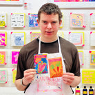 Male artist holding brightly coloured carrot seeds packet