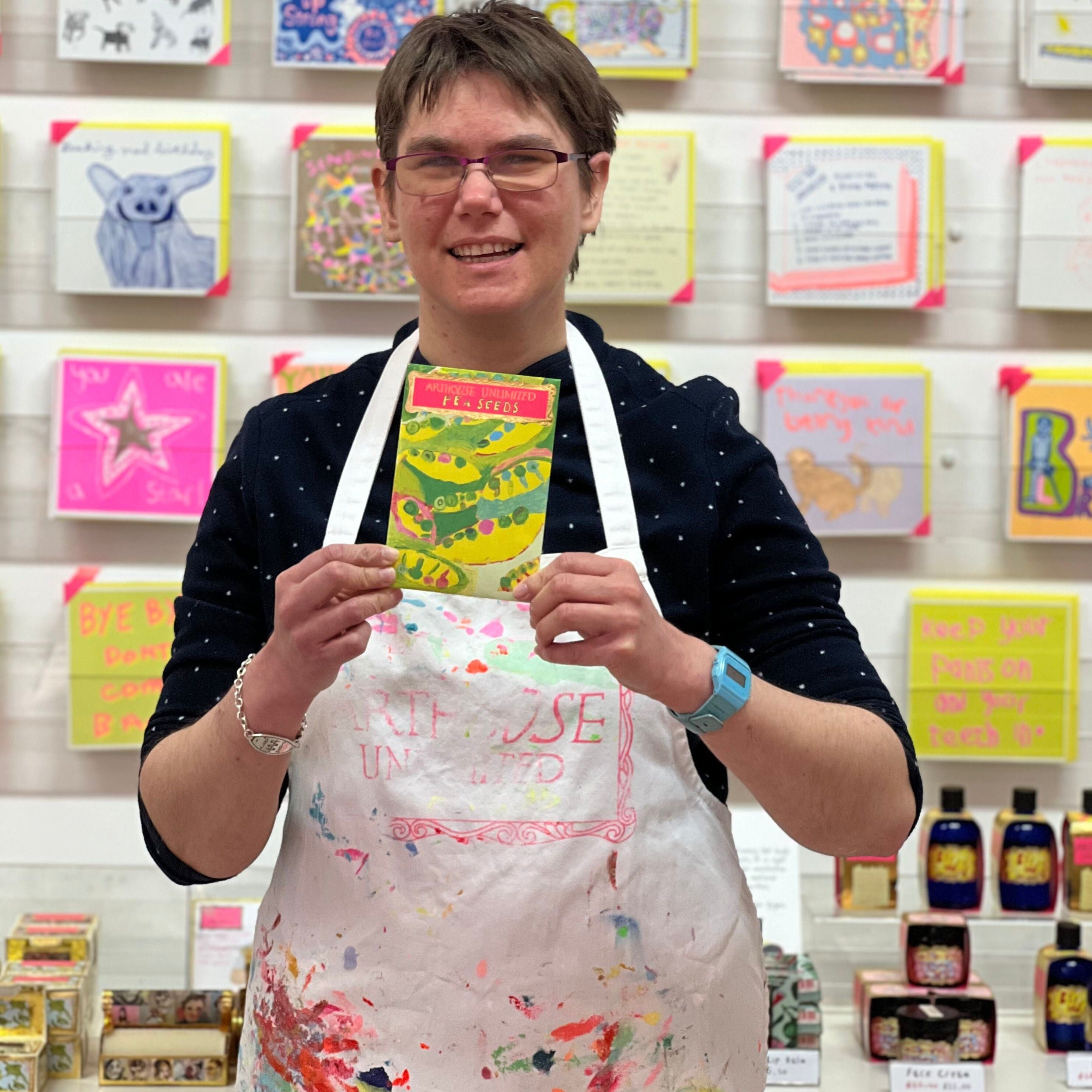 Female artist holding bright coloured Pea Seeds in greens and pinks