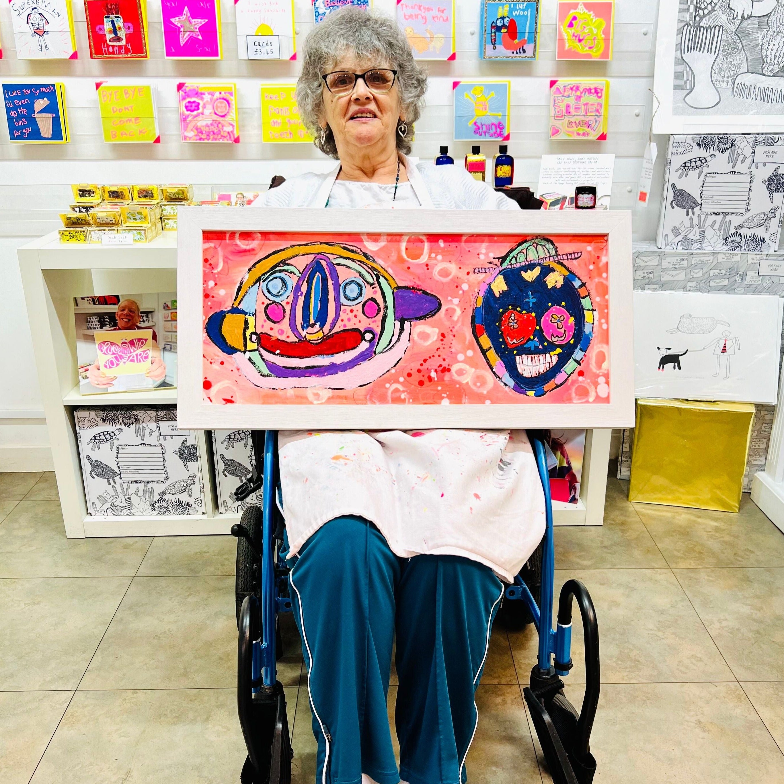 female artist holding Framed colourful abstract painting of two characters in bright colours