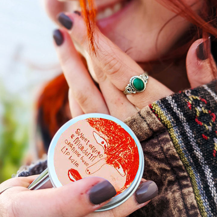 A young girl holding a tin of Lady Muck, Lip Balm, Sweet Orange & Mandarin