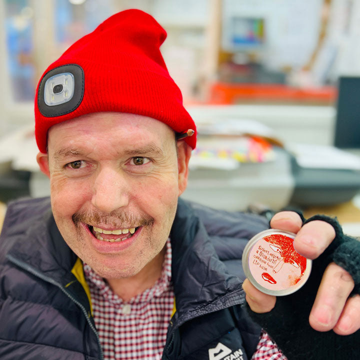 Male artist holding a ton of Lady Muck, Lip Balm, Sweet Orange & Mandarin
