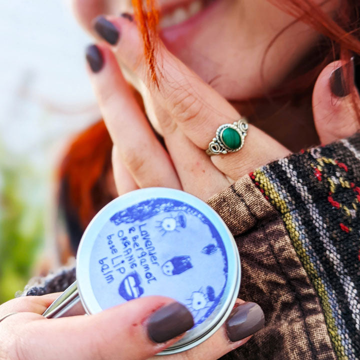 A young girl holding a tin of Lady Muck, Lip Balm, Lavender & Bergamot