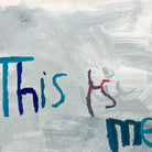 Close up of painting of the words 'this is me' in blues and greys 