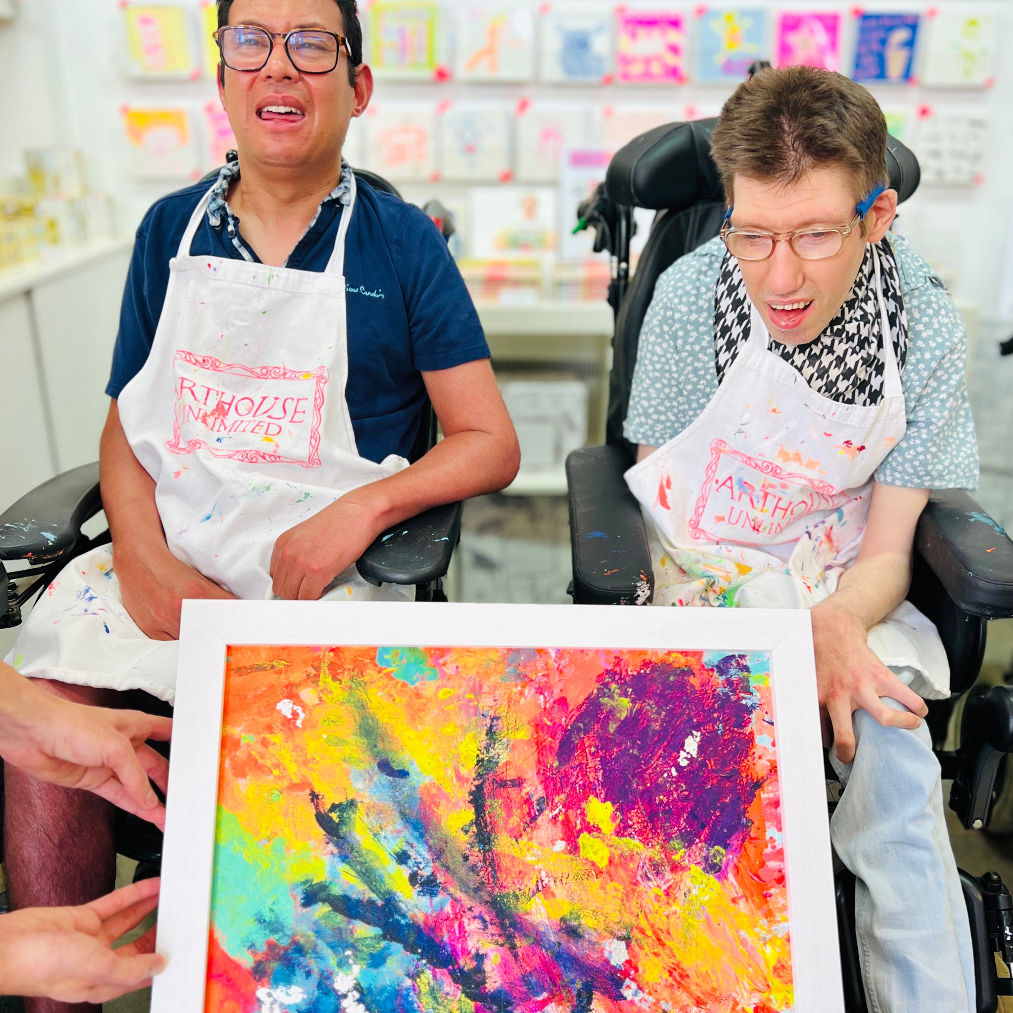 Two male artists holding Framed bright coloured abstract artwork called Sunset in the Clouds