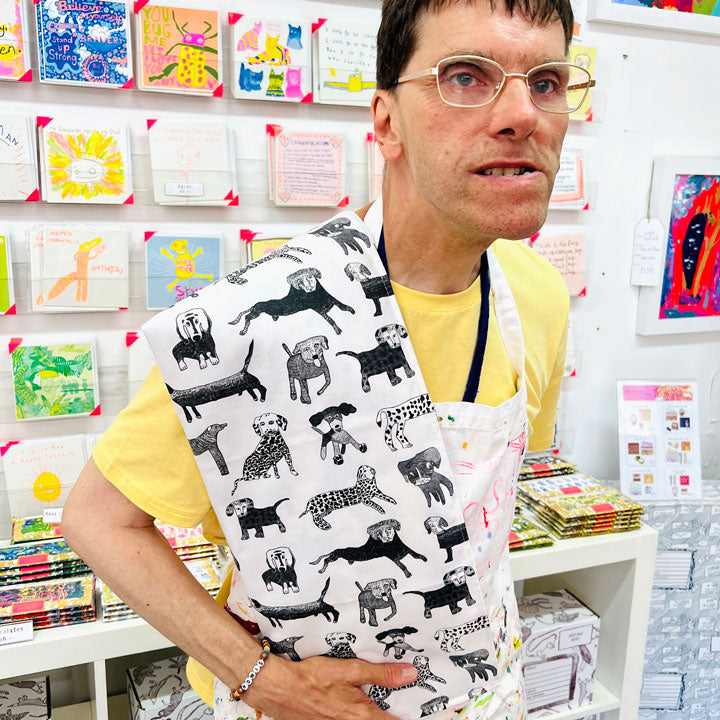 Male artist holding Dogalicious, 100% Organic Cotton Tea Towel with black dogs