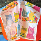 Miaow for Now, 100% Organic Cotton Tea Towel over the back of a chair