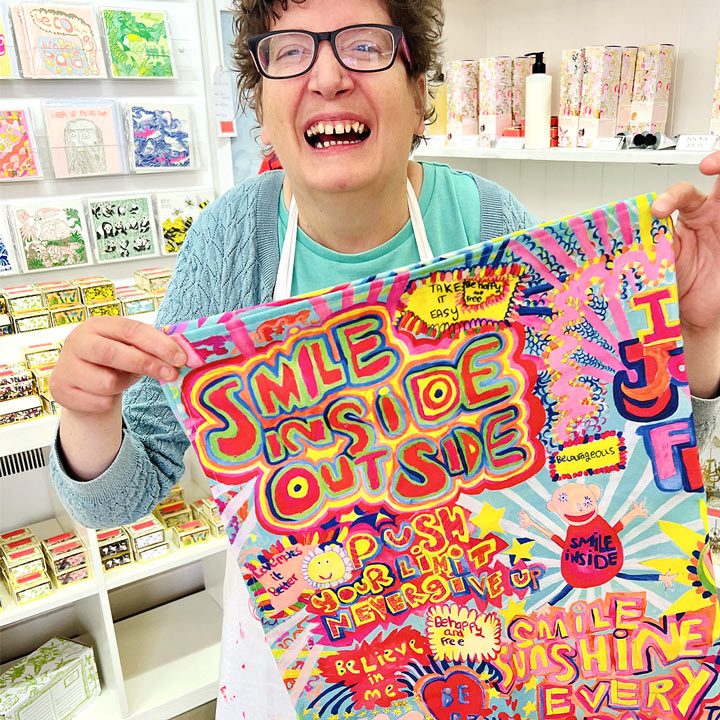 Female artist holding bright coloured Full of Joy, 100% Organic Cotton Tea Towel