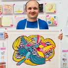 Male artist holding Framed drawing of four blue, yellow and pink birds