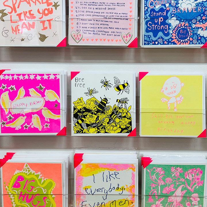 A rack of cards focusing on White greetings card with a yellow and black hand drawn be design with the words Bee Free