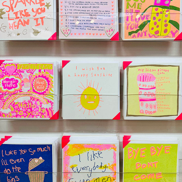 A card rack focusing on A white card with a hand drawn yellow and orange sun with the words I wish you a happy sunshine