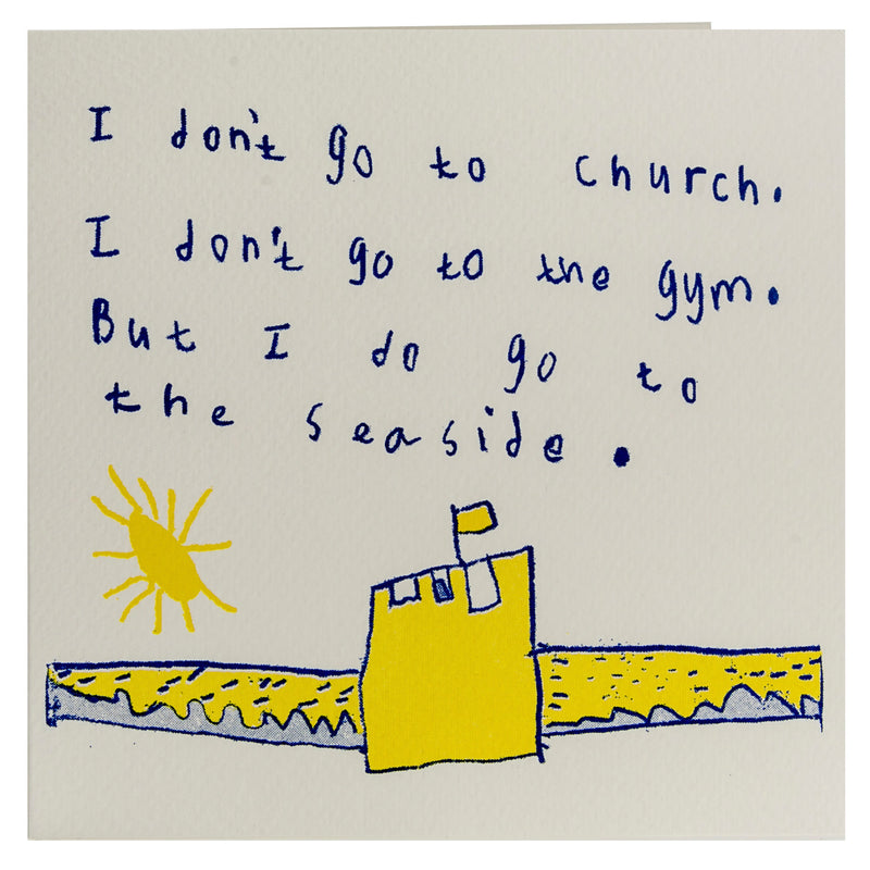 A white card with a blue and yellow drawing of a sand castle with the words I don't go to church, I don't go to the Gym, but I do go to the seaside