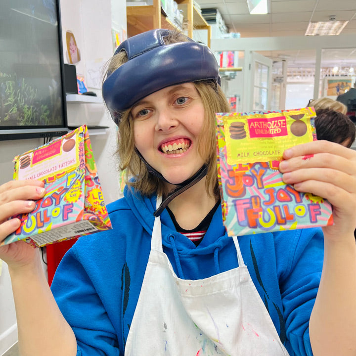 Female artist holding bright coloured packet of Full of Joy, Milk Chocolate Buttons