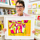 male artist holding Framed painting of a colourful cat in pink, green, orange and yellow