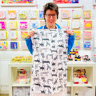 Female artist holding Dogalicious, 100% Organic Cotton Tea Towel with black sketched dogs 