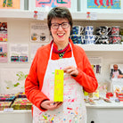 Artist holding box and bottle of Lady Muck, Body Lotion, Sweet Basil & Mandarin