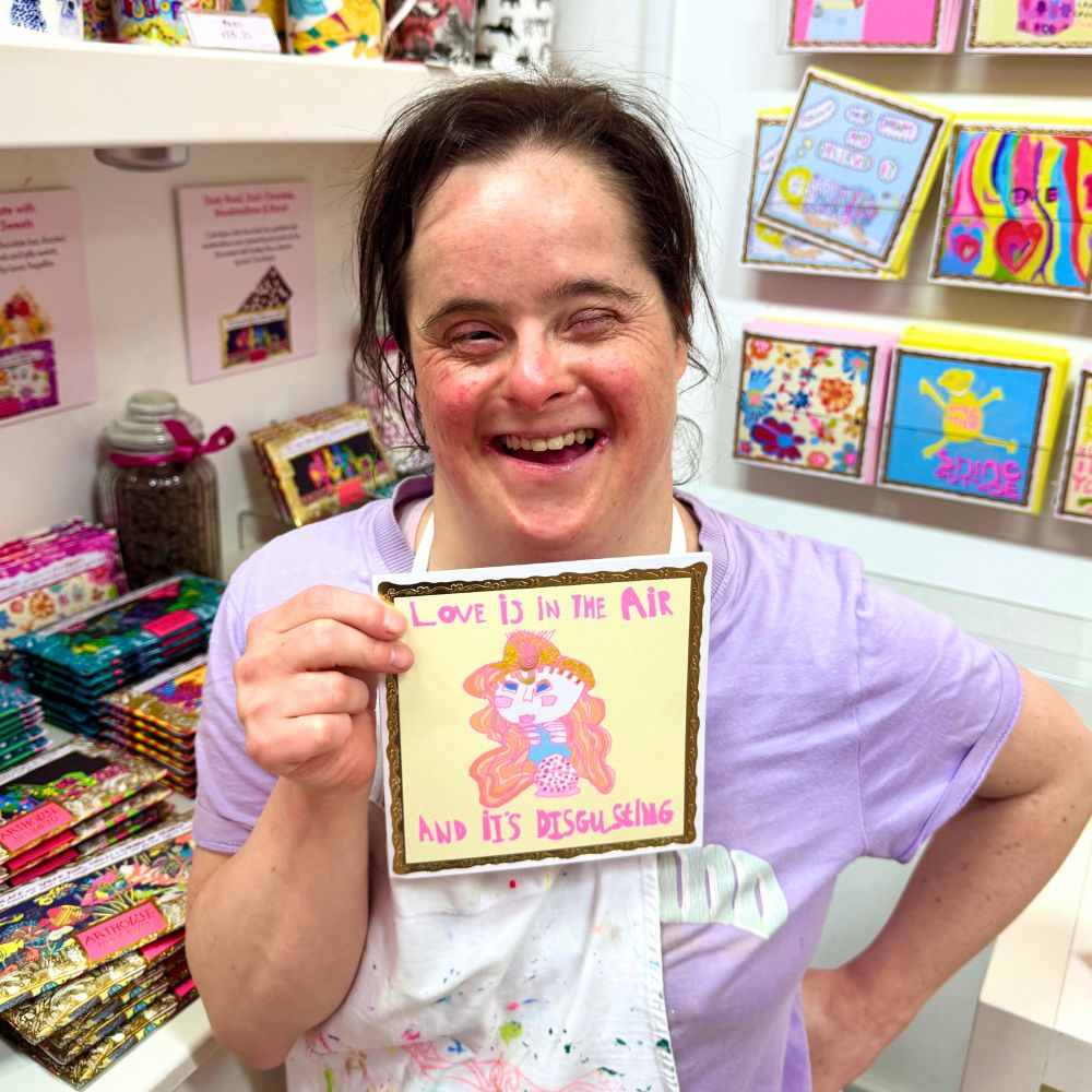 Artist Laura Cordwell laughs as she holds the card that she designed and illustrated.