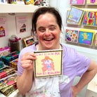 Artist Laura Cordwell laughs as she holds the card that she designed and illustrated.