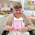 Artist Karen Brown smiles, and proudly holds the card she designed.