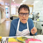 male artist holding Framed painting of a colourful cat in pink, green, orange and yellow