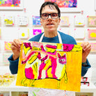 male artist holding Framed painting of a colourful cat in pink, green, orange and yellow