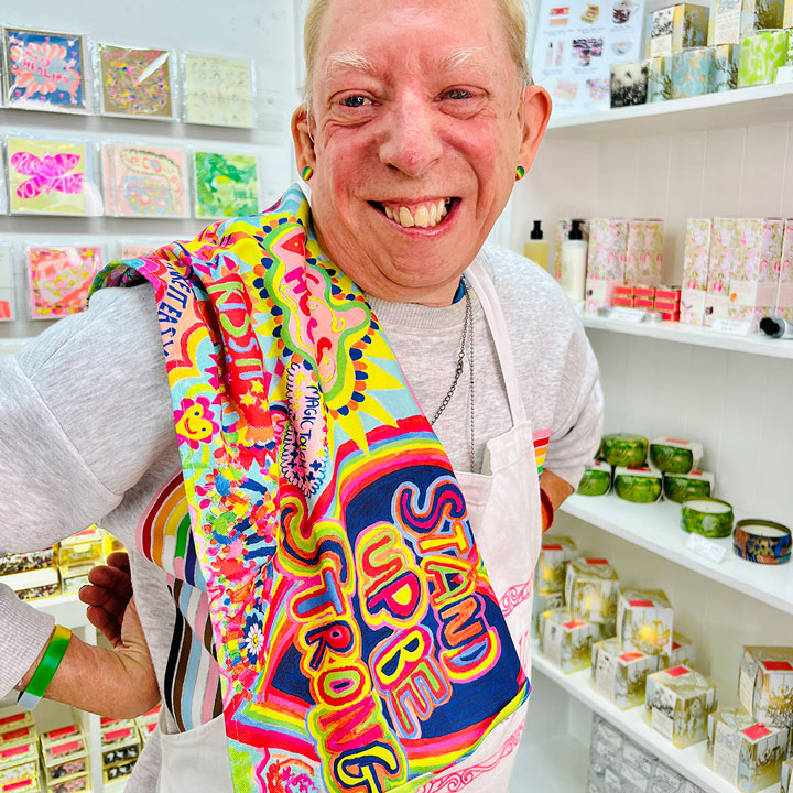 Male artist holding bright coloured Full of Joy, 100% Organic Cotton Tea Towel