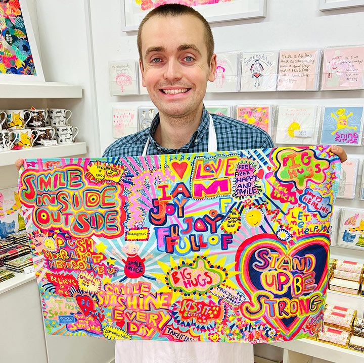 Male artist holding bright coloured Full of Joy, 100% Organic Cotton Tea Towel